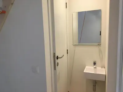a white bathroom with a sink and a mirror at Les Cerises, charmante maison au calme in Wavre