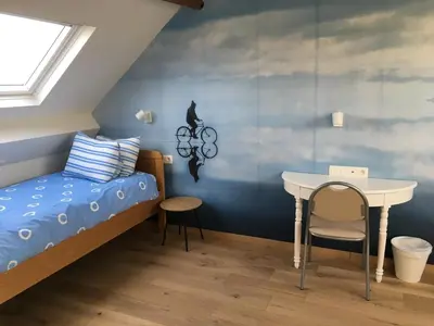 a small bedroom with a bed and a table at Les Cerises, charmante maison au calme in Wavre