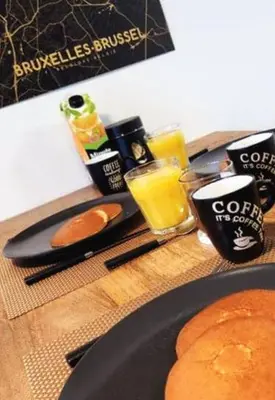 a table topped with a plate of pancakes and orange juice at BRUSSELS EXPO APARTMENT in Brussels