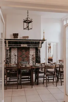 a dining room with a fireplace and a table and chairs at Bleyckhof in een uniek natuurgebied in Ranst