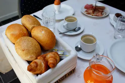 a table with a tray of bread and cups of coffee at De Kasteelhoeve in Westmalle