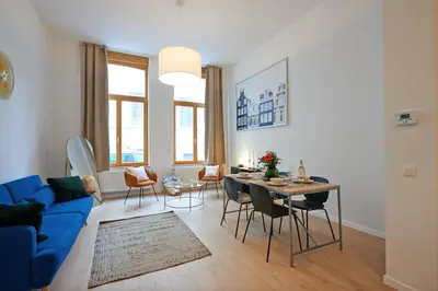 a living room with a blue couch and a table at South Cosy Residence in Brussels