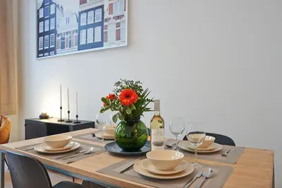 a table with a vase of flowers and a bottle of wine at South Cosy Residence in Brussels