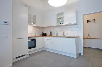 a white kitchen with white cabinets and appliances at South Cosy Residence in Brussels