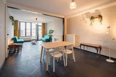 a dining room with a table and chairs and a room with windows at Two-Bedroom Apartments in the Heart of Antwerp in Antwerp