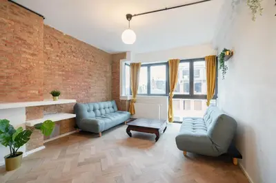 a living room with two blue couches and a brick wall at Two-Bedroom Apartments in the Heart of Antwerp in Antwerp