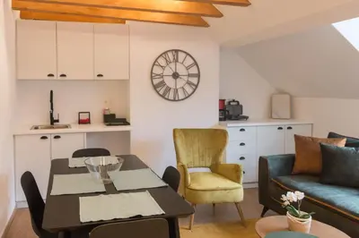 a living room with a table and a couch and a clock at QUARTIER LOUISE STUDIOS in Brussels