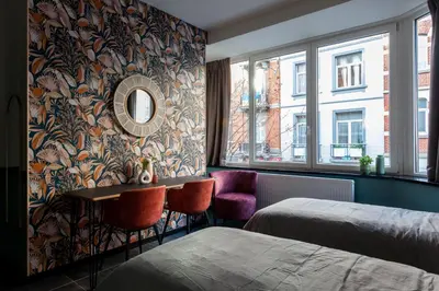 a hotel room with a bed and a table and chairs at Hey - Aparthotel Brussels in Brussels