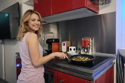 a woman in a kitchen preparing a bowl of food at Logeerkamer XXL 25 m2 in Zemst