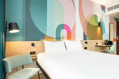 a room with two beds and a table and chairs at B&B HOTEL Mechelen in Mechelen