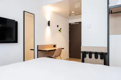 a room with a bed and a desk and a mirror at B&B HOTEL Mechelen in Mechelen