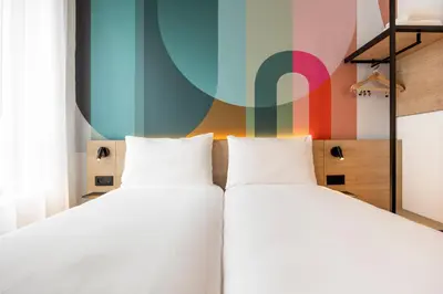 two beds in a room with a colorful wall at B&B HOTEL Mechelen in Mechelen