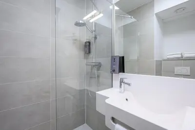 a bathroom with a shower and a sink and a mirror at B&B HOTEL Mechelen in Mechelen