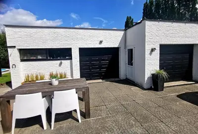 a patio with a wooden table and chairs and a building at Luxury Pop Up Camping & Hotel Package & Private Transport to Tomorrowland in Schelle