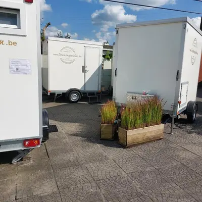 two white trucks parked in a parking lot with plants at Luxury Pop Up Camping & Hotel Package & Private Transport to Tomorrowland in Schelle