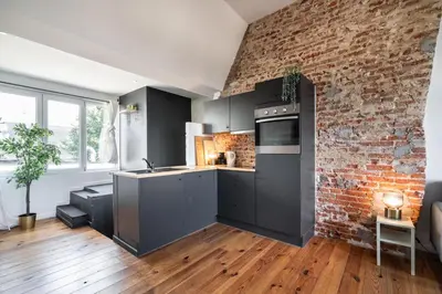 a kitchen with black cabinets and a brick wall at Two-Bedroom River Side Apartment in the Heart of Antwerp in Antwerp