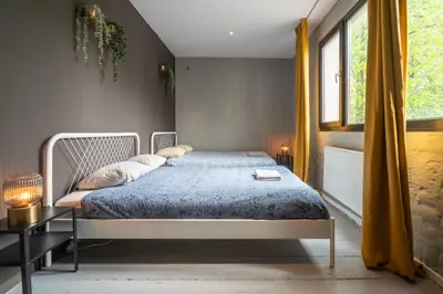 a bedroom with a bed with a blue comforter and a window at Two-Bedroom River Side Apartment in the Heart of Antwerp in Antwerp