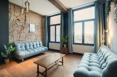 a living room with blue couches and a table and windows at Two-Bedroom River Side Apartment in the Heart of Antwerp in Antwerp