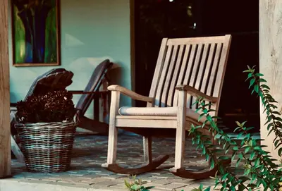 a rocking chair sitting on a porch next to a basket at Huis van luut in Tielt
