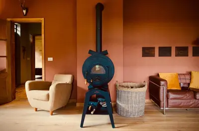 a wood stove in a living room with two chairs at Huis van luut in Tielt
