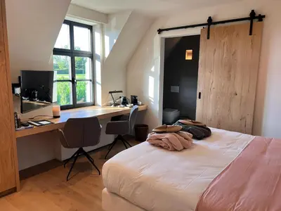 a bedroom with a bed and a desk with a computer at B&B 't Kloosterveld in Boutersem