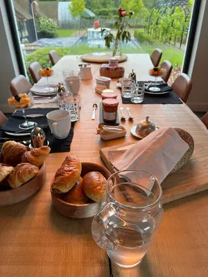 a long wooden table with bread and pastries on it at B&B 't Kloosterveld in Boutersem