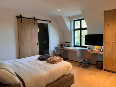 a bedroom with a bed and a desk with a computer at B&B 't Kloosterveld in Boutersem