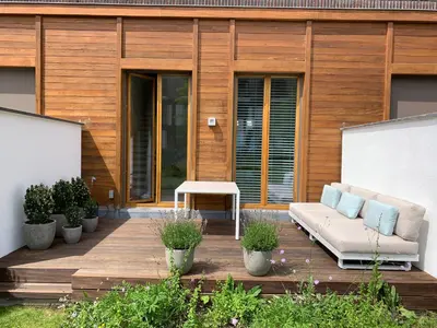 a patio with a couch on a wooden deck at Luxury apartment, private terrace & FREE PARKING in Antwerp