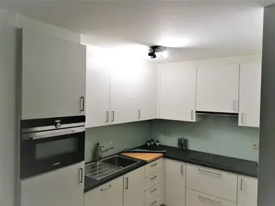 a white kitchen with white cabinets and a sink at The Corner in Retie