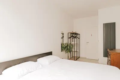 a bedroom with a white bed and a wooden dresser at Cozy Apartment in Brussels in Brussels