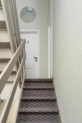 a hallway with stairs with a white door and a light at Studio Anvers in Antwerp