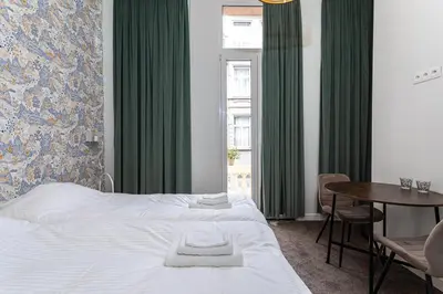a bedroom with a bed and a table and green curtains at Studio Anvers in Antwerp
