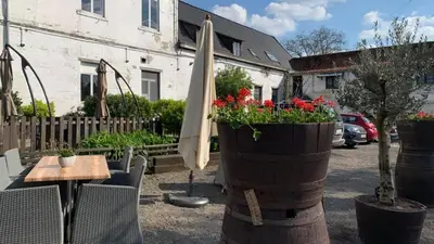 a patio with a table and an umbrella and flowers at Sweet Dreams by Pegase in Vlezenbeek