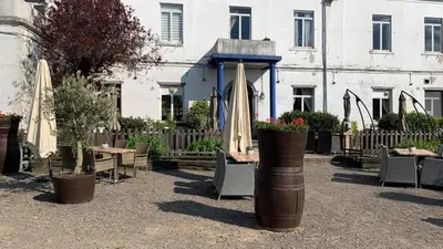 a patio with tables and umbrellas in front of a building at Sweet Dreams by Pegase in Vlezenbeek