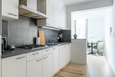 a kitchen with white cabinets and a sink and a table at Bright, Spacious Apartments & Perfectly Located in the Heart of Ghent in Ghent