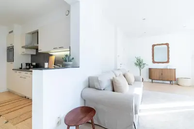 a white living room with a couch and a kitchen at Bright, Spacious Apartments & Perfectly Located in the Heart of Ghent in Ghent
