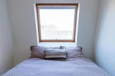 a bed with a pillow in front of a window at Bright, Spacious Apartments & Perfectly Located in the Heart of Ghent in Ghent