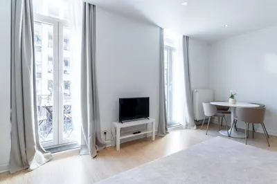 a white living room with a tv and a table at Bright, Spacious Apartments & Perfectly Located in the Heart of Ghent in Ghent