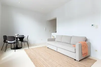 a white living room with a couch and a table at Bright, Spacious Apartments & Perfectly Located in the Heart of Ghent in Ghent