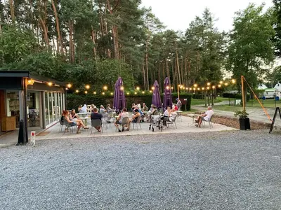 a group of people sitting at tables in a park at Camping het Swinnenbos in Diest