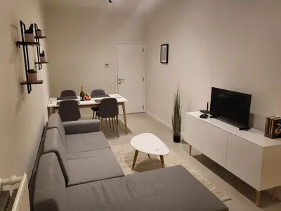 a living room with a couch and a tv and a table at Huis ALNA 3 in Mechelen