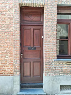a wooden door on the side of a brick building at Huis ALNA 3 in Mechelen