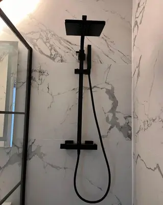 a shower head in a bathroom with a marble wall at Hôtel La Pièce in Brussels
