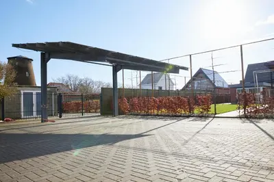 a tennis court with a pavilion in front of a fence at Holiday Home De Steenen Molen in Brecht