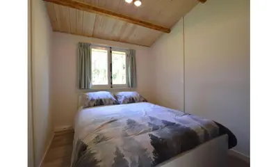 a bed in a small room with a window at Bungalow aan de Visbeekvallei in Vlimmeren