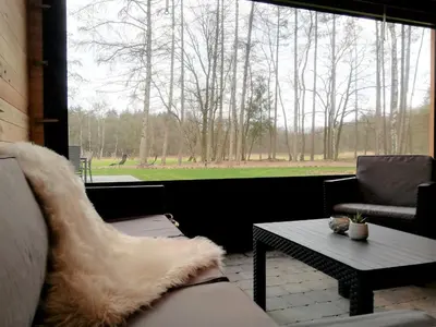 a living room with a couch and a table and a large window at Bungalow aan de Visbeekvallei in Vlimmeren