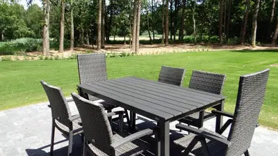 a wooden table and chairs sitting on a patio at Bungalow aan de Visbeekvallei in Vlimmeren