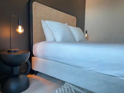 a bedroom with a bed and a table with a lamp at Historic 3 Bedroom Art-Nouveau Apartment with Airconditioning - Walk to Station Gent Sint-Pieters & Close to City Centre in Ghent
