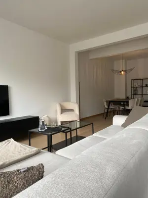 a living room with white furniture and a dining room at Cosy Apartment near Antwerp in Mortsel