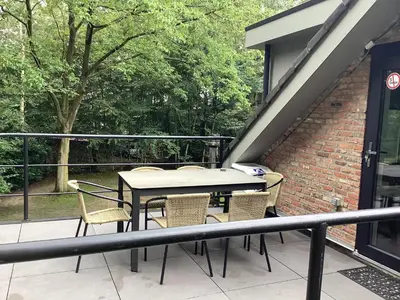 a patio with a table and chairs on a balcony at Vakantiewoningeikenhof in Londerzeel